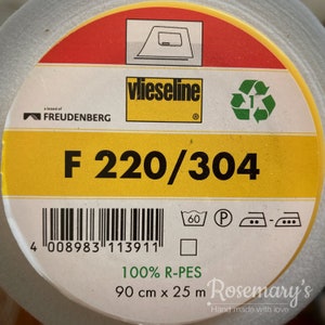 May include: A roll of white Vlieseline F 220/304 interfacing, a brand of Freudenberg, with a green recycling symbol and care instructions. The label indicates it is 100% R-PES, 90 cm x 25 m.
