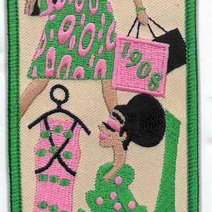 May include: Green and pink embroidered patch with two women in dresses and shopping bags. The text "1908" is on one of the bags.
