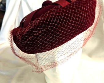 Vintage 1950s-60s "Styled by Coralie" Maroon Pillbox hat, covered with net, Top Ribbon Decor, very good condition.  Clean. Ships free.
