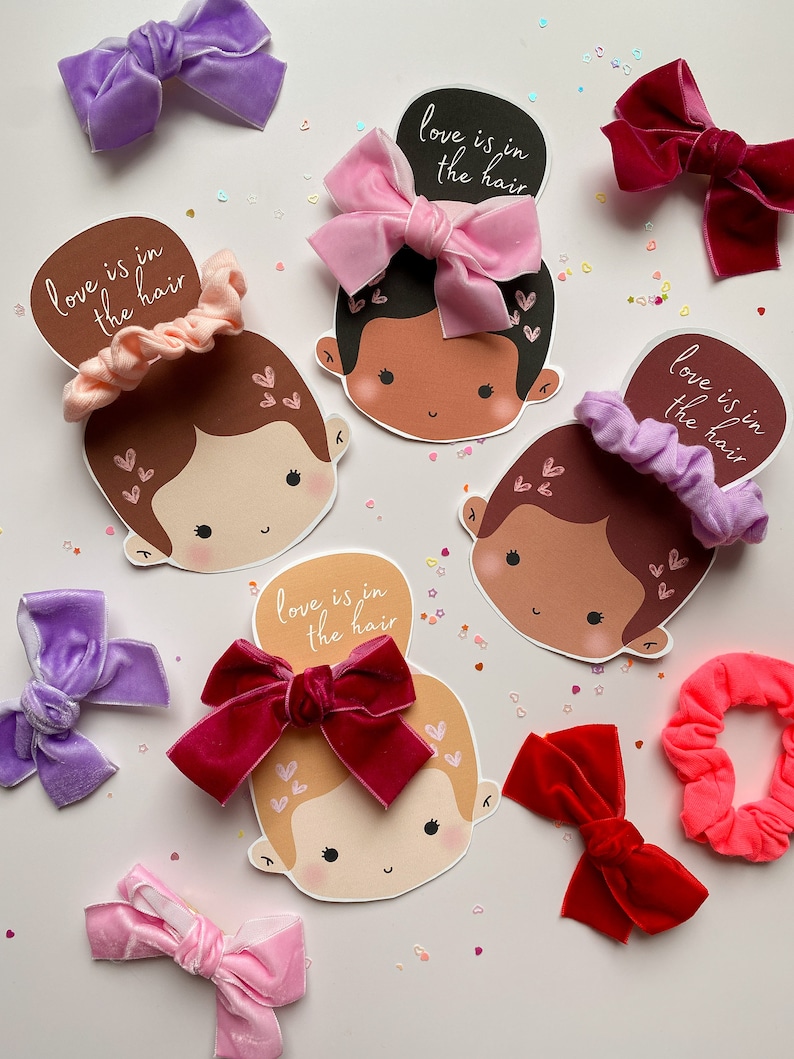 Puede incluir: Cuatro tarjetas ilustradas con caras de dibujos animados y el texto "love is in the hair". Cada tarjeta presenta un accesorio para el cabello diferente: un lazo de terciopelo rosa, un scrunchie morado, un lazo de terciopelo rojo y un scrunchie rosa.