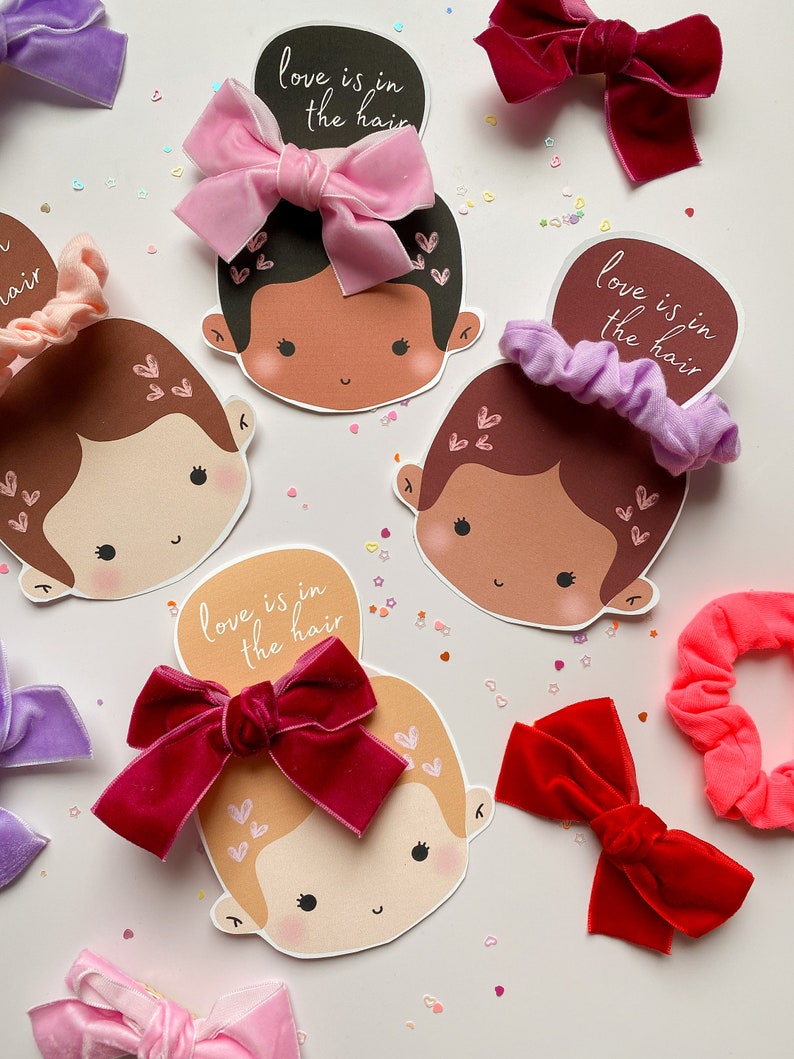 Puede incluir: Cuatro caras ilustradas con el texto "love is in the hair" en cada una. Cada cara tiene un lazo para el pelo de un color diferente, incluyendo rosa, rojo, morado y un scrunchie marr&oacute;n.