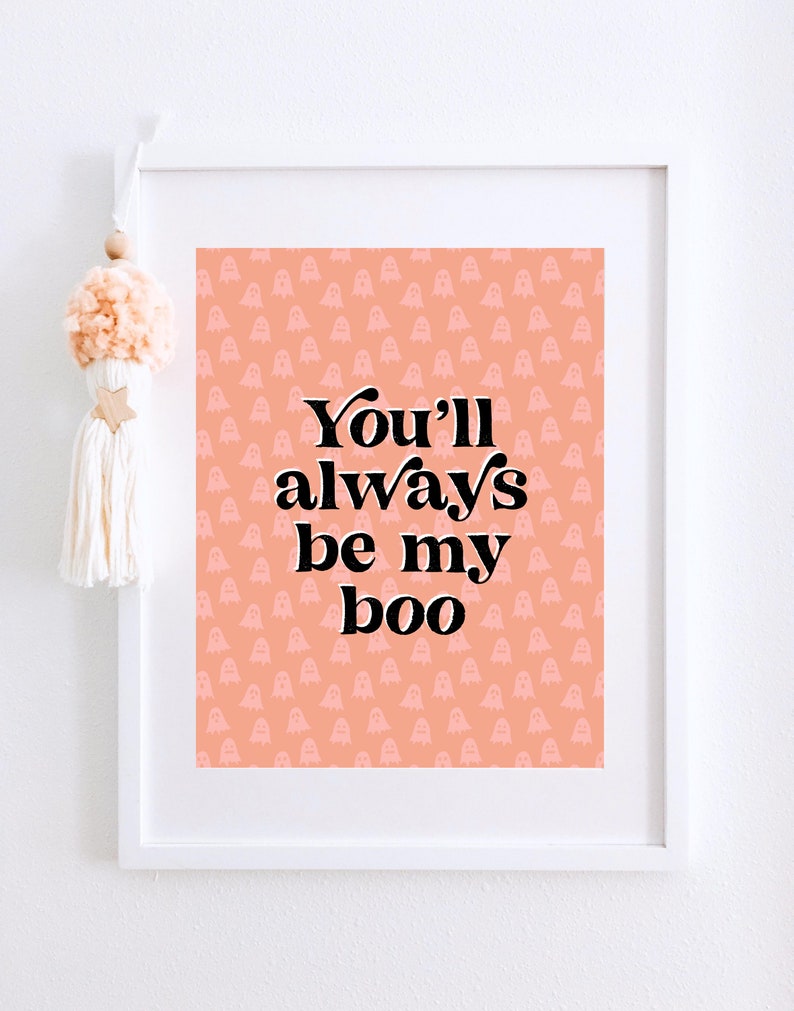 May include: A framed print with a peach background and a pattern of white ghosts. The print says "You'll always be my boo" in black text.