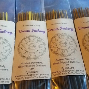 Puede incluir: Cuatro paquetes de varillas de incienso de lavanda con una etiqueta marrón que dice "Lavender Blend Dream Factory Custom Blended, Hand Dipped Incense By Symbolry www.symbolrydesigns.com Proudly Made In The East Bay". Cada etiqueta presenta un diseño circular con símbolos y texto.