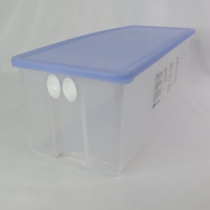 May include: A clear plastic storage container with a light blue lid. The container has two white handles on the side and is designed for organizing items. The lid has a textured surface.