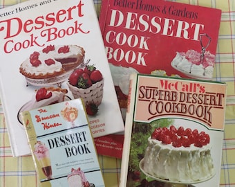May include: A collection of vintage dessert cookbooks, including titles like "Better Homes and Gardens Dessert Cook Book" and "McCall's Superb Dessert Cookbook." The books feature images of cakes, pies, and strawberries. The books are on a yellow and white checkered tablecloth.