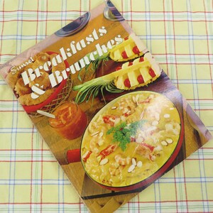 May include: A vintage cookbook titled "Sunset Breakfasts & Brunches" featuring images of breakfast and brunch dishes. The cover displays a basket of croissants, a jar of marmalade, and a casserole dish with a creamy sauce.