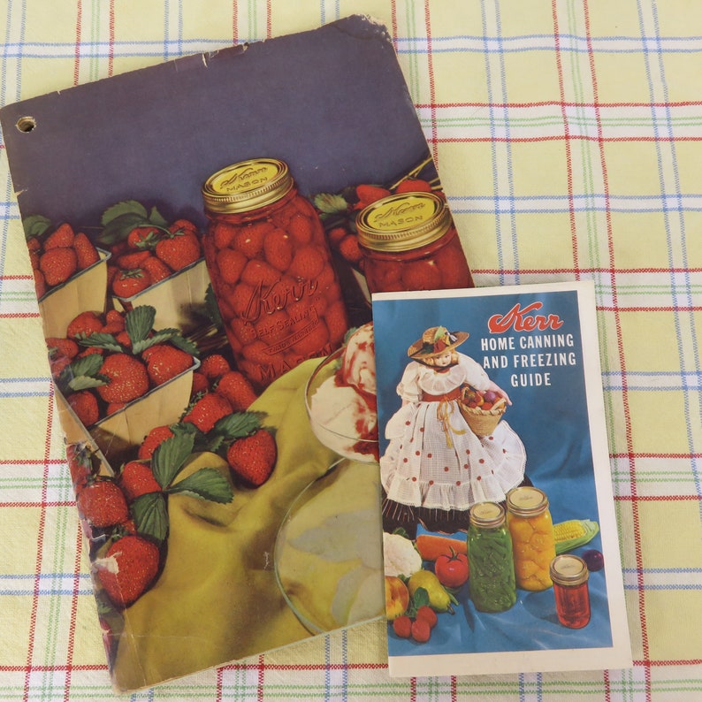 May include: Vintage Kerr home canning guide and brochure featuring illustrations of strawberries, jars of preserves, and a woman with a basket of fruit. The brochure is on a yellow and white checkered surface.