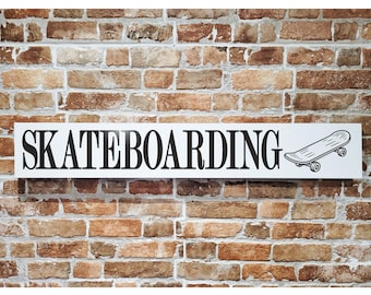 May include: A white rectangular sign with the word "SKATEBOARDING" in black, accompanied by a black and white illustration of a skateboard. The sign is mounted on a brick wall with varying shades of brown and tan bricks.