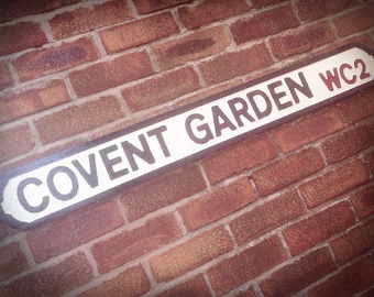 May include: A white sign with black lettering on a brick wall reads "COVENT GARDEN WC2".