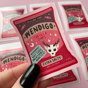 May include: A pink and red sticker with a cartoon illustration of a deer skull with antlers. The sticker is shaped like a bag of chips and has the text "Wendigo. Folklore Food. Tortilla Chips. Warning! May cause insatiable appetite! Extra Salty. 100% Natural. 400g"