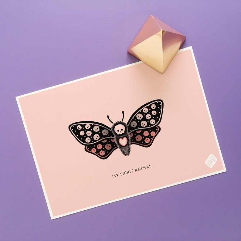 May include: A pink and white card with a black and white butterfly illustration. The butterfly has a heart in the center and is surrounded by skulls. The text "My Spirit Animal" is printed below the butterfly.