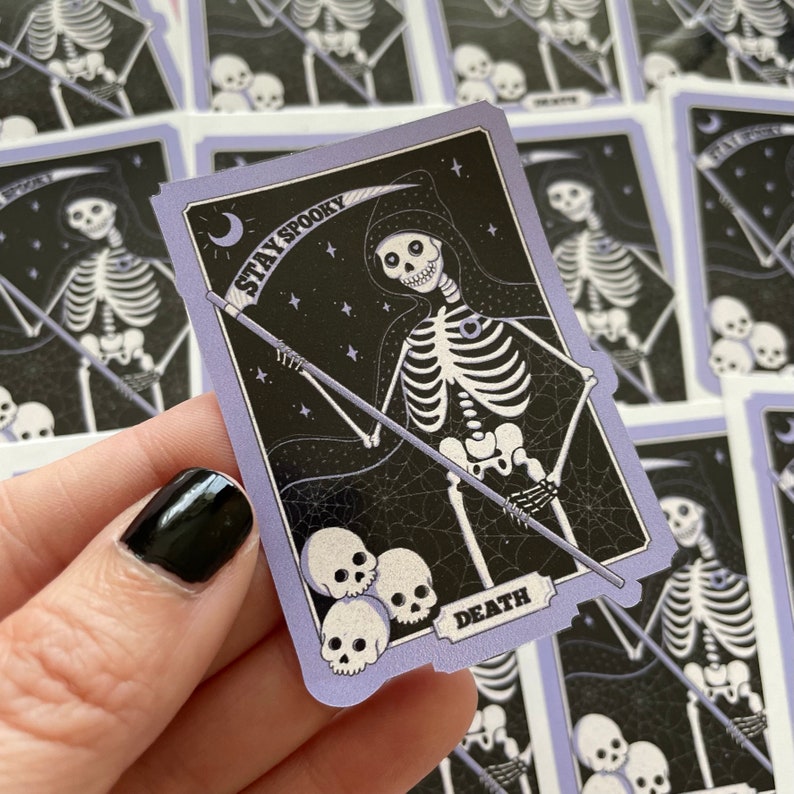 May include: A purple and black tarot card with a skeleton holding a scythe. The card says "Stay Spooky" and "Death".