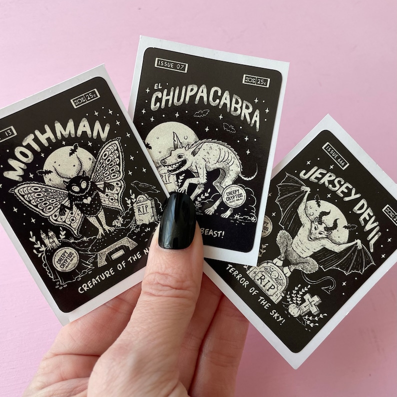 May include: Three black and white illustrated trading cards featuring mythical creatures. The cards are titled "Mothman", "El Chupacabra", and "Jersey Devil". Each card has a creepy cryptids logo and a tagline.