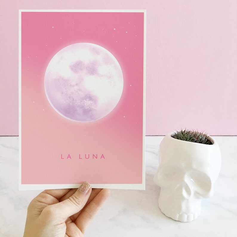 May include: A pink and purple illustration of a full moon with the text "LA LUNA" printed below. The image is printed on a white card.