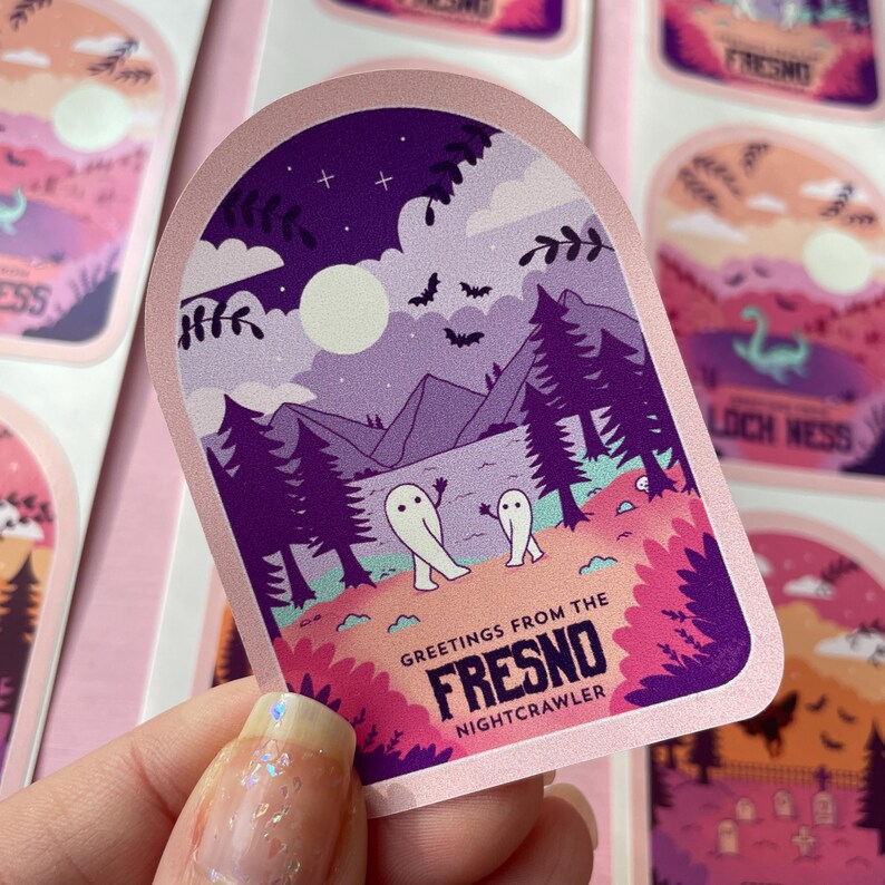 K&ouml;nnte beinhalten: Ein rosa und lilafarbener Aufkleber mit einer Nachtszene eines Waldes, Bergen und einem Vollmond. Zwei wei&szlig;e Geister gehen im Vordergrund. Der Aufkleber lautet "Greetings from the Fresno Nightcrawler".