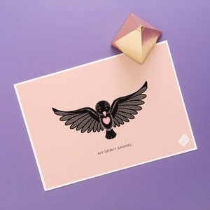 May include: A pink card with a black bird illustration with a pink heart on its chest. The text "My Spirit Animal" is printed below the bird.