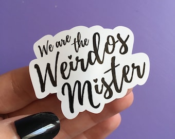 May include: White sticker with black text that reads "We are the Weirdos Mister".