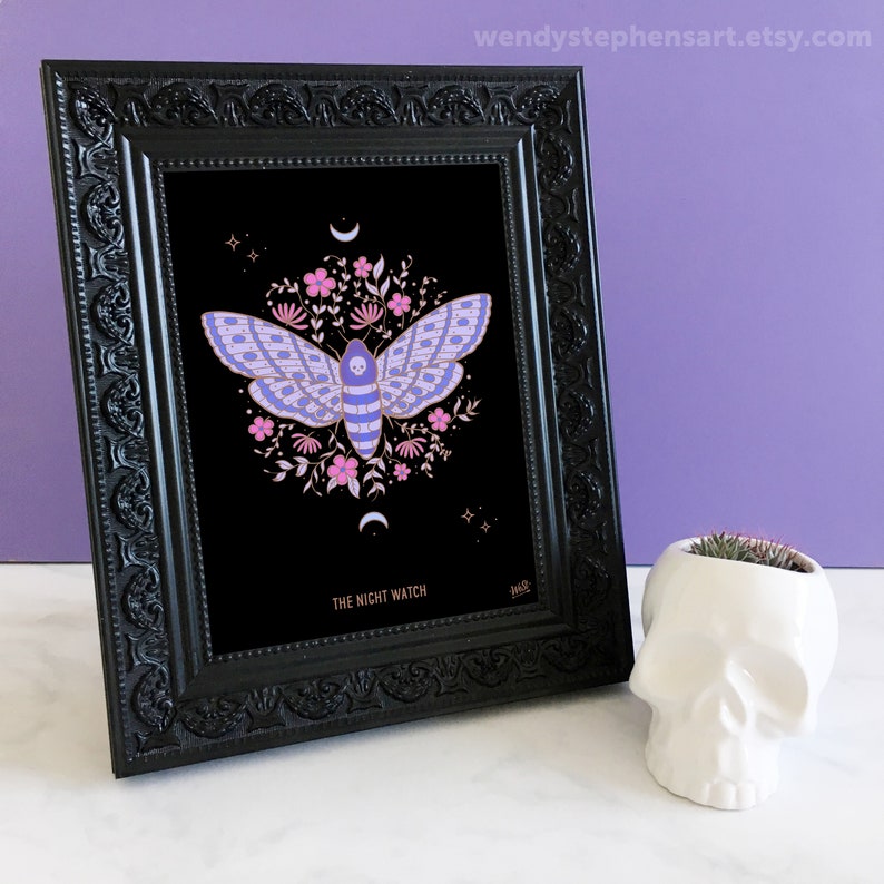 May include: A framed print of a moth with pink and purple wings, surrounded by flowers and a crescent moon. The print is on black paper and has the text "The Night Watch" at the bottom.