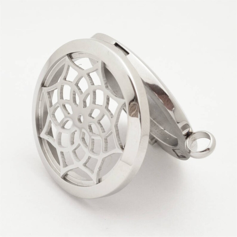 May include: Silver-toned metal locket with a circular design featuring a mandala-like pattern. The locket opens to reveal a space for essential oils or other small items.