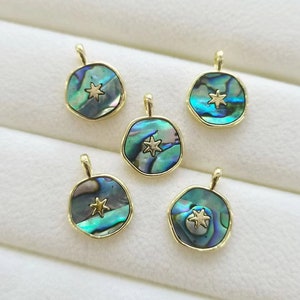 Może przedstawiać: Pięć złotych zawieszek z okrągłym wzorem z muszli abalone. Każda zawieszka ma złotą gwiazdę w środku.