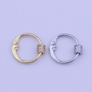 May include: Two crescent moon shaped rings with a small cylinder of clear cubic zirconia stones in the center of each ring. The ring on the left is gold and the ring on the right is silver.