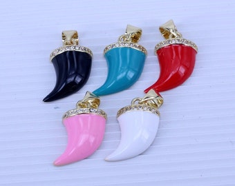 Puede incluir: Cinco colgantes de tono dorado en forma de cuerno con una fila de diamantes de imitación transparentes alrededor de la parte superior. Los cuernos son de diferentes colores: negro, turquesa, rojo, rosa y blanco.