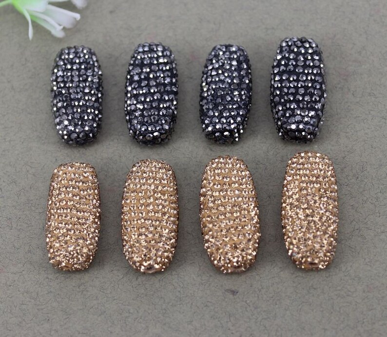May include: Eight oval-shaped rhinestone embellishments, four are black and four are gold.