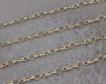 May include: Gold chain with a delicate, linked design. The chain is made of small, oval-shaped links that are connected to form a continuous pattern.