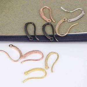 Puede incluir: Surtido de ganchos para pendientes en varios acabados, incluyendo oro, plata y negro. Los ganchos son de metal y tienen una forma curva. Están diseñados para usar con pendientes.