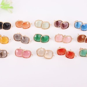 May include: Assortment of 12 pairs of square-shaped earrings with gold-tone settings. The earrings feature a variety of colors, including black, orange, yellow, green, gray, pink, red, and blue.