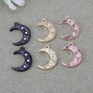 Pode incluir: Seis pingentes de lua crescente com um design de estrela. Tr&ecirc;s pingentes s&atilde;o pretos, tr&ecirc;s s&atilde;o dourados e tr&ecirc;s s&atilde;o de ouro rosa. Cada pingente tem cinco strass transparentes.
