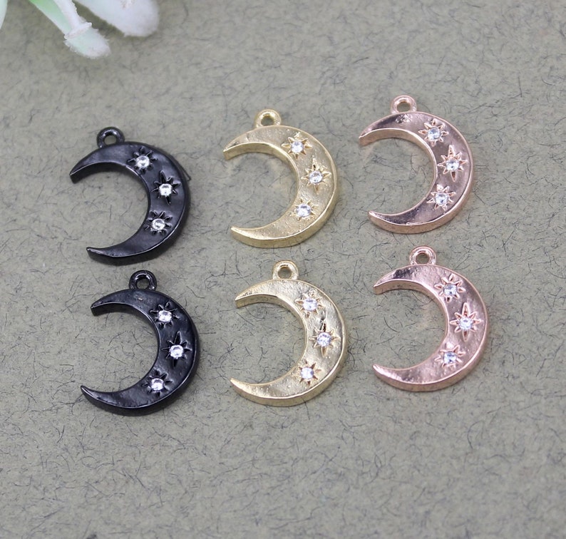 Pode incluir: Seis pingentes de lua crescente com um design de estrela. Tr&ecirc;s pingentes s&atilde;o pretos, tr&ecirc;s s&atilde;o dourados e tr&ecirc;s s&atilde;o de ouro rosa. Cada pingente tem cinco strass transparentes.