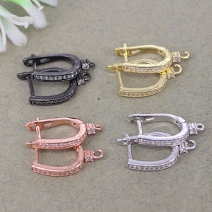 Puede incluir: Cuatro pares de cierres de pendientes con un diseño de aro. Los aros están adornados con una fila de piedras de cristal transparentes. Los cierres están disponibles en negro, oro, oro rosa y plata.
