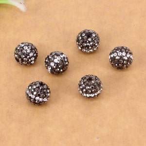 May include: Seven black round beads with a silver sparkle finish. Each bead is covered in small, closely spaced rhinestones.
