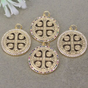 May include: Four gold-toned pendants with a circular design featuring a cross with four smaller circles around it. The pendants are adorned with clear and colorful rhinestones around the edges.