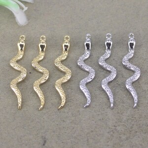 May include: Six gold and silver snake charm pendants. The snake charms are detailed with a textured, scaly design. The charms are all the same size and shape, but are in two different finishes: gold and silver.