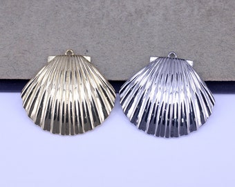 May include: Two metal seashell charms, one gold and one silver, with a textured, ribbed design. The charms are perfect for jewelry making or crafting.