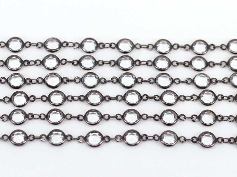May include: A black chain with clear round crystal beads. The chain is made of metal and has a polished finish.