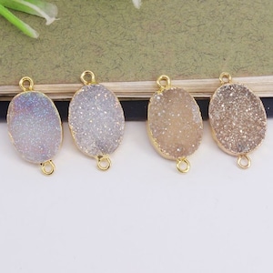 May include: Four oval-shaped agate gemstone pendants with gold-toned jump rings. The agate is white with a sparkly, iridescent finish.