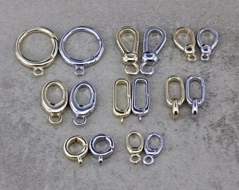 May include: An assortment of metal clasps and connectors in gold and silver tones. The collection includes round, oval, and rectangular shapes, as well as lobster claw clasps and spring rings. These findings are suitable for jewellery making and crafting projects.