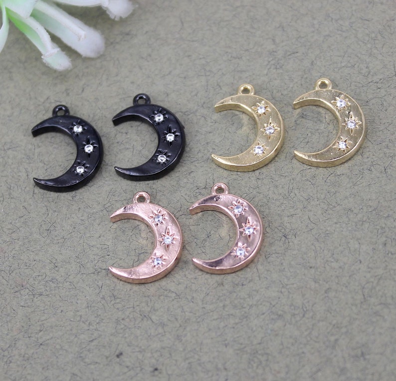 Pode incluir: Seis pingentes de lua crescente com um design de estrela. Dois pingentes s&atilde;o pretos, dois s&atilde;o dourados e dois s&atilde;o dourados rosados.