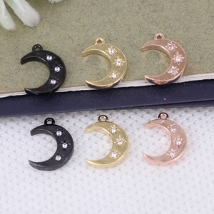Pode incluir: Seis pingentes de lua crescente com strass. Os pingentes est&atilde;o em tr&ecirc;s acabamentos diferentes: preto, dourado e dourado rosa.