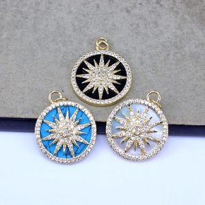 May include: Three round pendants with a sunburst design. One pendant has a black background, one has a turquoise background, and the third has a white background. All have gold-colored frames and are adorned with small, sparkling stones.