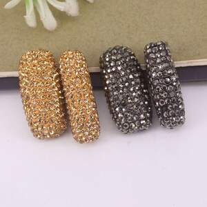 May include: Two gold and two black rhinestone-covered rectangular beads. The beads are about 1 inch long and 1/2 inch wide.