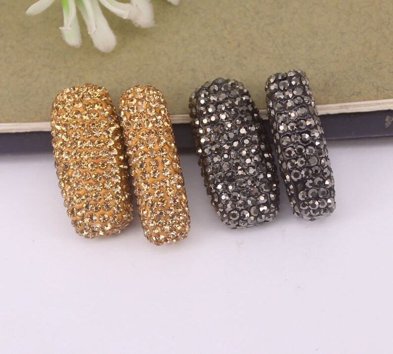 May include: Two gold and two black rhinestone-covered rectangular beads. The beads are about 1 inch long and 1/2 inch wide.