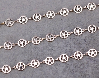 May include: Three gold chains with star-shaped cutouts in each link. The chains are layered on a gray surface.