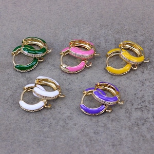 May include: Six pairs of hoop earrings with colourful enamel and clear rhinestone accents. The earrings are in shades of green, pink, yellow, white, and purple.