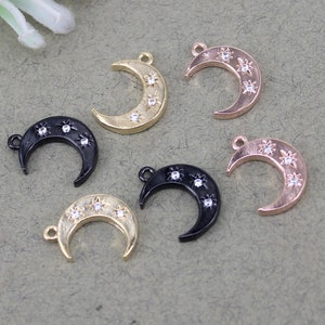 Pode incluir: Seis pingentes em forma de lua crescente com um design de estrela. Os pingentes est&atilde;o em tr&ecirc;s acabamentos diferentes: ouro, preto e ouro rosa.