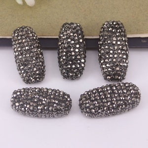 May include: Five black, rectangular, faceted beads made of rhinestones. The beads are approximately 1 inch long and 1/2 inch wide.