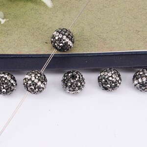 May include: Six black and silver round beads with a sparkly finish. The beads are strung on a silver wire.